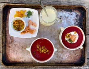 Beet soup on tray with garnishes: dill, diced beet, smoked salmon and creme fraiche.